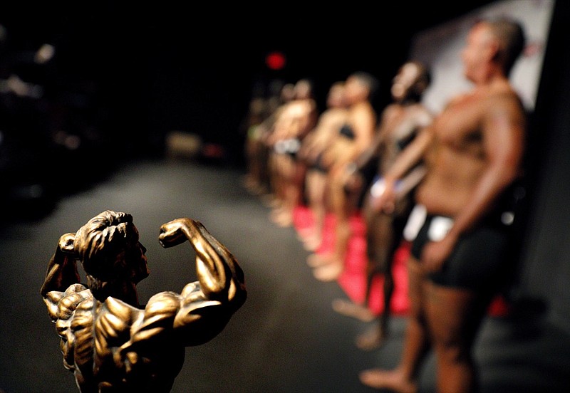 A trophy sits on display as contestants line up in front of the crowd at the International Association of Trans Bodybuilders competition in Atlanta, Saturday, Oct. 6, 2018. The competition, in its fifth year, is the only transgender bodybuilding competition in the world and has drawn competitors from across the country and one from Russia. (AP Photo/David Goldman)