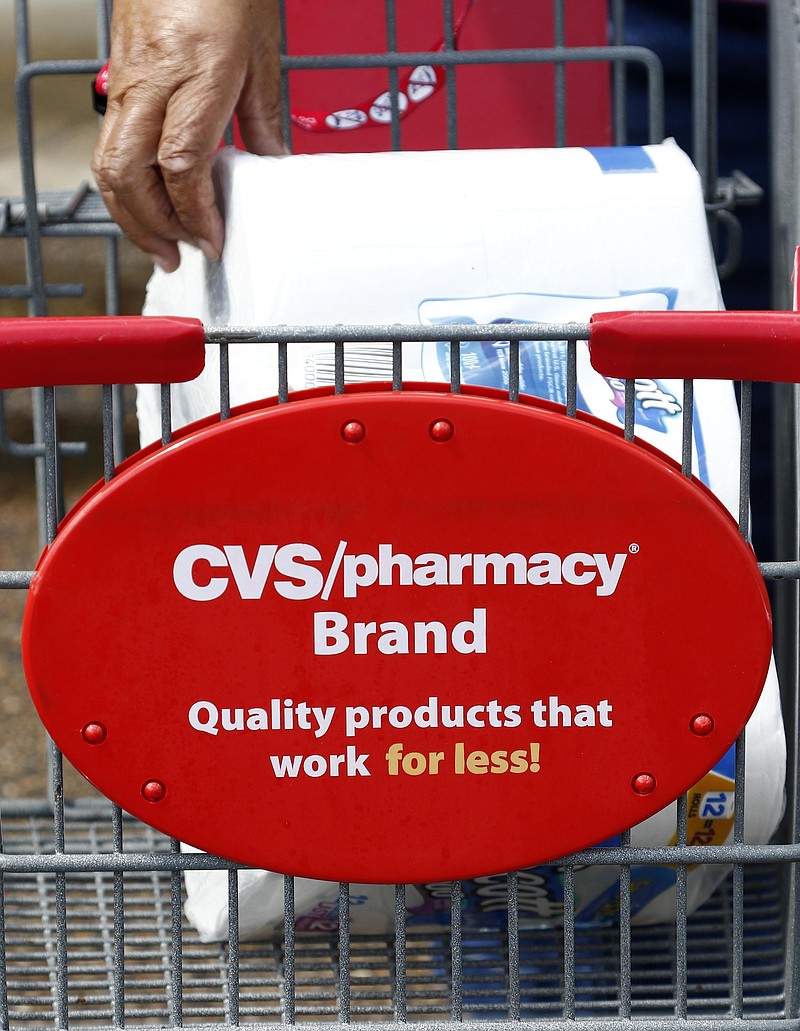 In this Aug. 7, 2018, photo a customer removes her purchases from a CVS Pharmacy cart in Jackson, Miss. (AP Photo/Rogelio V. Solis)