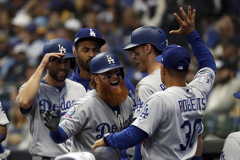 Los Angeles Dodgers third baseman Justin Turner, center, celebrates with manager Dave Roberts and teammates after hitting a two-run home run during the eighth inning of Game 2 of the NLCS against the Milwaukee Brewers on Saturday afternoon.