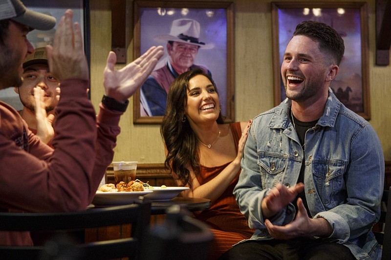Contestant Josh Davis, right, smiles and applauds during a private viewing party with friends and family for "The Voice" at Big Tom's Backyard Grill and Bar on Monday, Oct. 15, 2018, in Cleveland, Tenn. Davis joined Team Kelly.