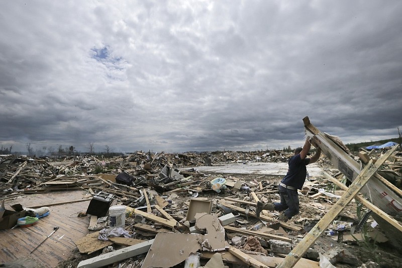 In this April 30, 2014, file photo, Dustin Shaw lifts debris as he searches through what is left of his sister's house at Parkwood Meadows neighborhood after a tornado in Vilonia, Ark. A new study finds that tornado activity is generally shifting eastward to areas just east of the Mississippi River that are more vulnerable such as Mississippi, Arkansas and Tennessee. And it's going down in Oklahoma, Kansas and Texas. (AP Photo/Danny Johnston, File)