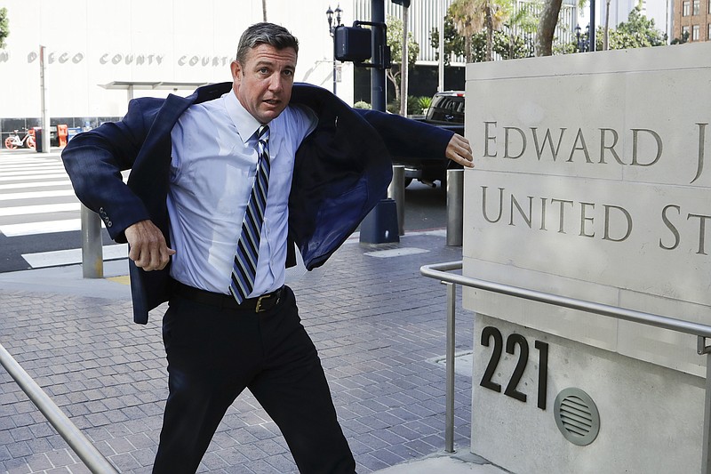 In this Aug. 23, 2018 photo, Rep. Duncan Hunter, R-Calif., pulls on his coat as he arrives for an arraignment hearing in San Diego. Winning re-election while indicted is a rare feat in U.S. history. But two congressmen are attempting to do just that in this midterm election: Rep. Duncan Hunter of California and Rep. Chris Collins of New York. The first Republican lawmakers to endorse President Donald Trump are now running low-profile campaigns, avoiding the media and meeting with voters at Republican friendly events.  (AP Photo/Gregory Bull)