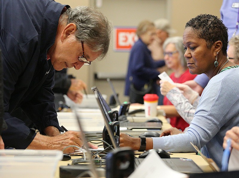 Jim Hamlin signs a piece of paper to signify his information is correct as he is helped by voting registrar Angela Humphries during early voting Wednesday, October 17, 2018 at Collegedale City Hall in Collegedale, Tennessee. Each voter was required to show government issued identification and confirm their current address before being able to vote. 