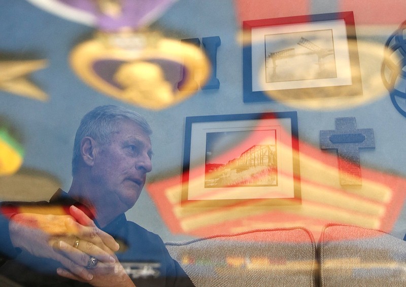 In a reflection on a shadowbox containing his medals and ribbons, Roger Helle talks about his service in the Vietnam War at his home Friday, October 12, 2018 in Ringgold, Ga. Helle was in the United States Marine Corps and suffered life-threatening injuries during his third tour. 