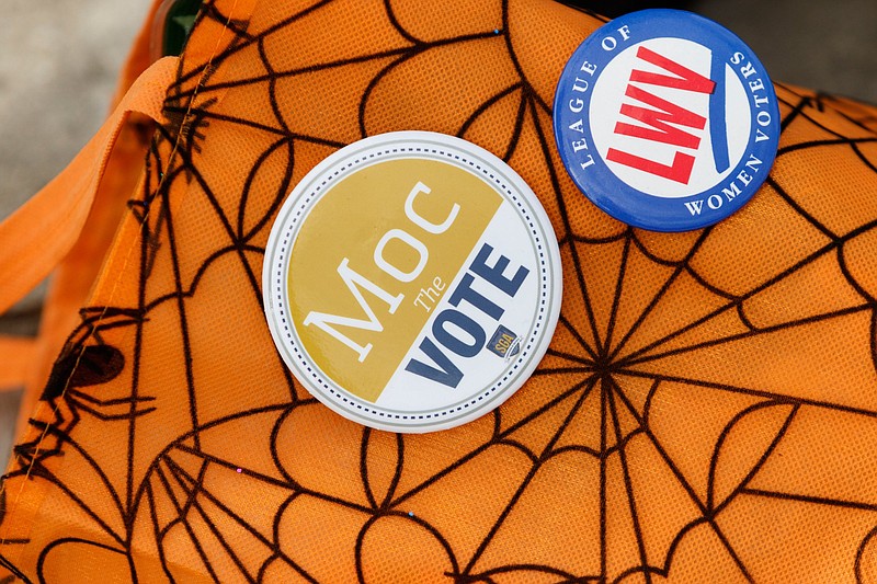League of Women Voters and Moc the Vote buttons are seen on Maria Sabin's bag as she informs students about early voting outside McKenzie Arena on Wednesday, Oct. 31, 2018, in Chattanooga, Tenn. President Donald Trump is expected to hold a pre-election day rally at the arena on Sunday.