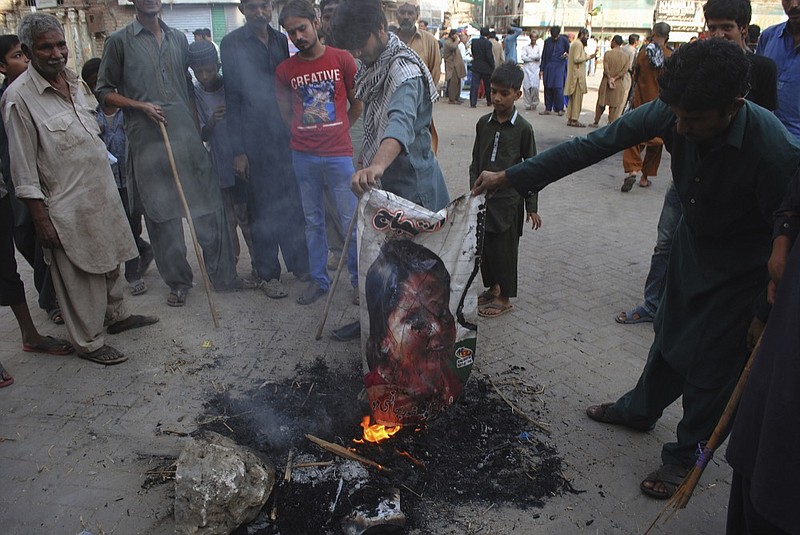 Pakistani protesters burn a poster image of Christian woman Asia Bibi, who has spent eight-years on death row accused of blasphemy and acquitted by a Supreme Court, in Hyderabad, Pakistan, Thursday, Nov. 1, 2018. Bibi plans to leave the country, her family said Thursday, as Islamists mounted rallies demanding Bibi be publicly hanged, and also called for the killing of the three judges, including Chief Justice Mian Saqib Nisar, who acquitted Bibi. (AP Photo/Pervez Masih


