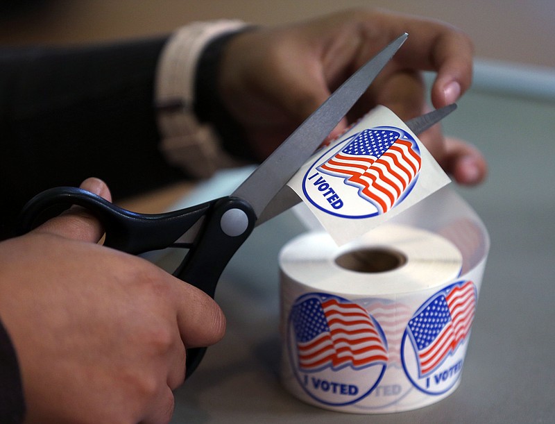 A volunteer hands out stickers to voters in Carson City, Nev., similar to what is done in many voting precincts across the nation on Election Day.