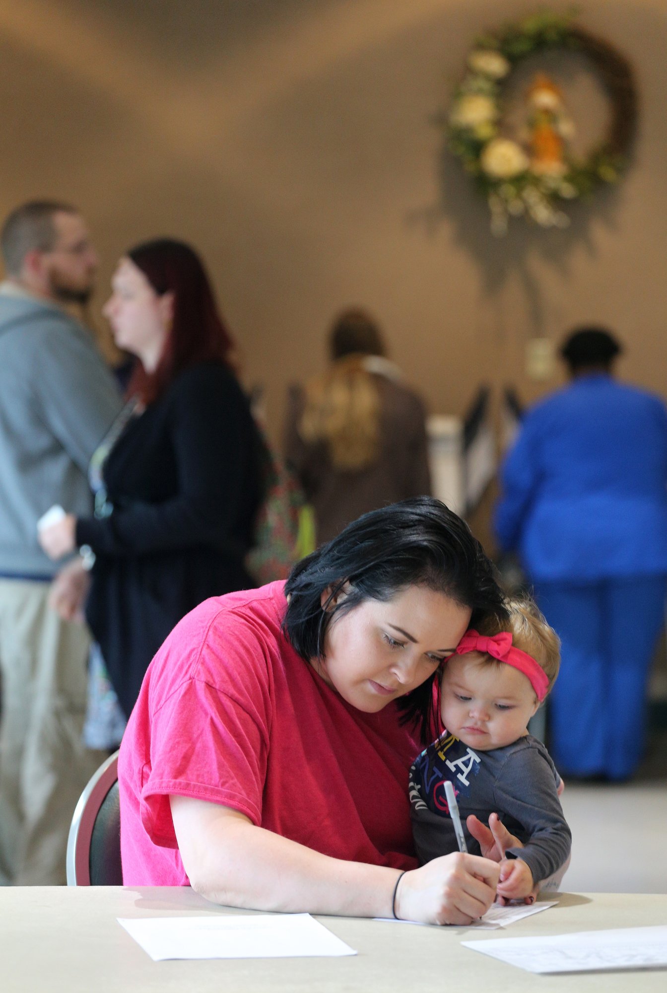 Emily Johnson holds her 10-month-old daughter Eleanor Johnson as she fills out information before voting Tuesday, November 6, 2018 at Rossville City Hall in Rossville, Georgia. The lines were fairly short at the precinct; however, there was a constant flow of voters throughout the day.