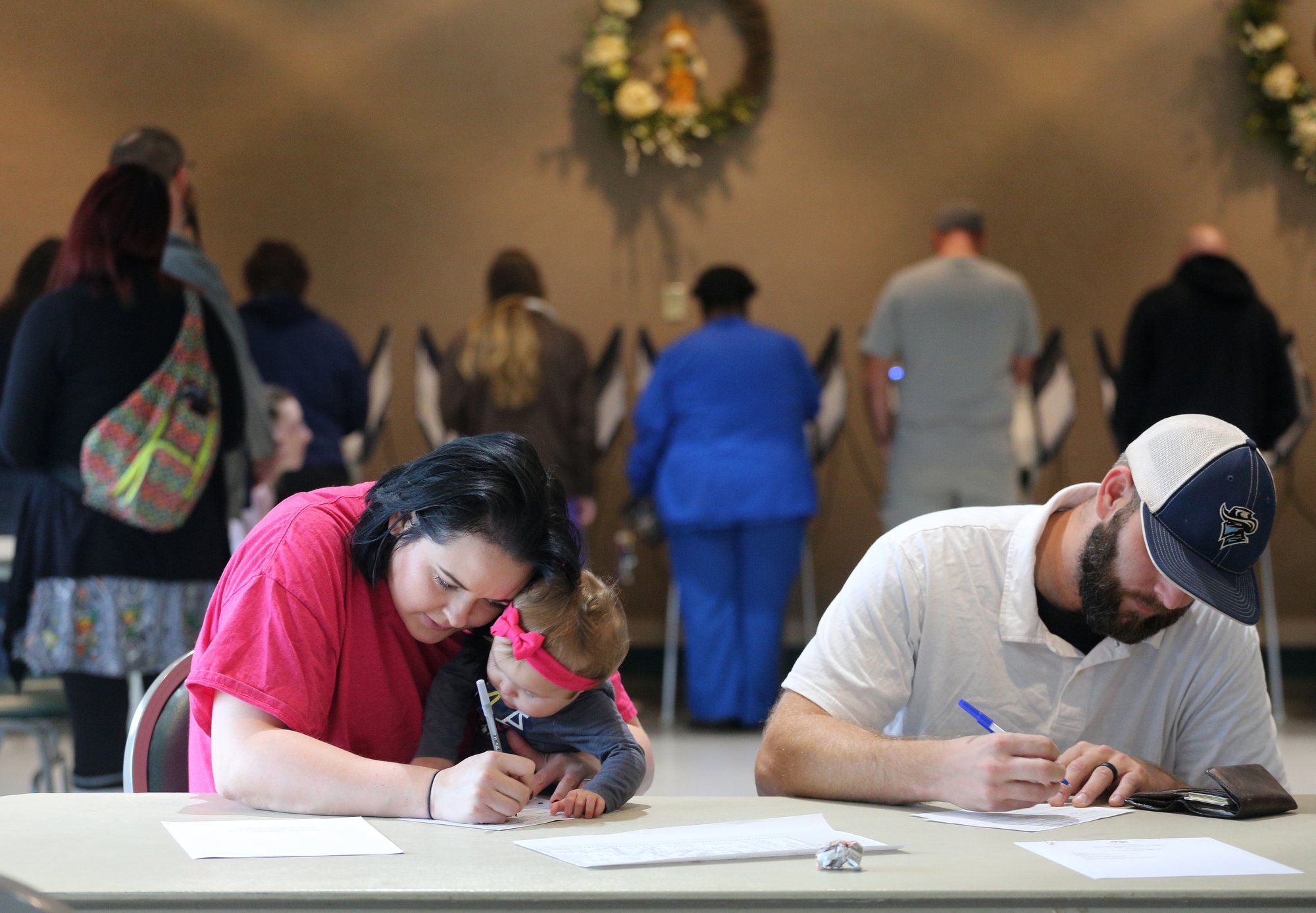 Emily Johnson holds her 10-month-old daughter, Eleanor Johnson, as she and her husband, Brandon Johnson, fill out information prior to voting Tuesday, November 6, 2018 at Rossville City Hall in Rossville, Georgia. The lines were fairly short at the precinct; however, there was a constant flow of voters throughout the day.