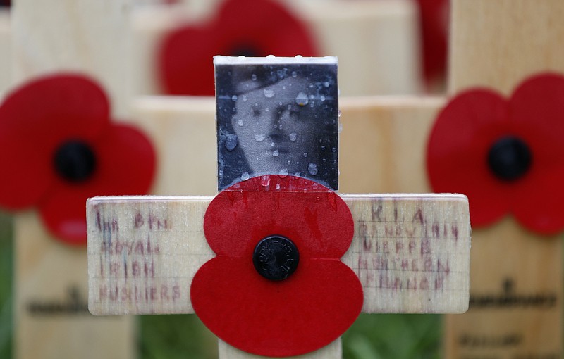 A rain drop covers a photograph of Gerald Briedell of the Royal Irish Regiment who was killed in action on Nov. 23, 1914, adorns a cross placed in the Field of Remembrance at Westminster Abbey in preparation for the annual Armistice Day commemoration for the dead and injured military and civilian in conflicts around the world on Nov. 11, in London, Wednesday, Nov. 7, 2018. (AP Photo/Alastair Grant)