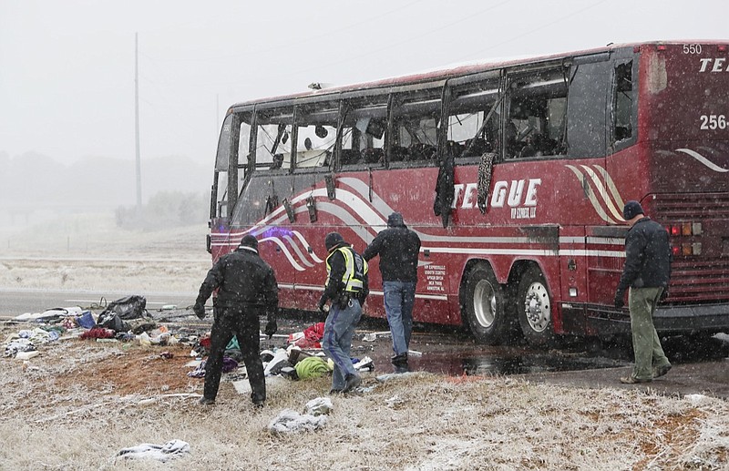 Law enforcement officers inspect the site where a tour bus carrying passengers overturned just after midday, Wednesday, Nov. 14, 2018, in DeSoto County, Miss. The crash came as a winter storm has been raking parts of the South. (Joe Rondone/The Commercial Appeal via AP)