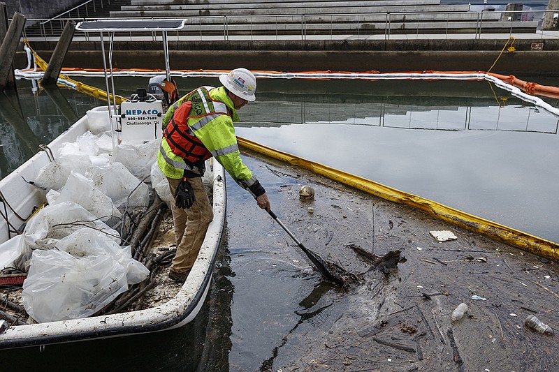 An environmental cleanup worker deploys booms in Citico Creek after a Jan. 8, 2018, spill leaked thousands of gallons of diesel fuel into the creek and the Tennessee River.