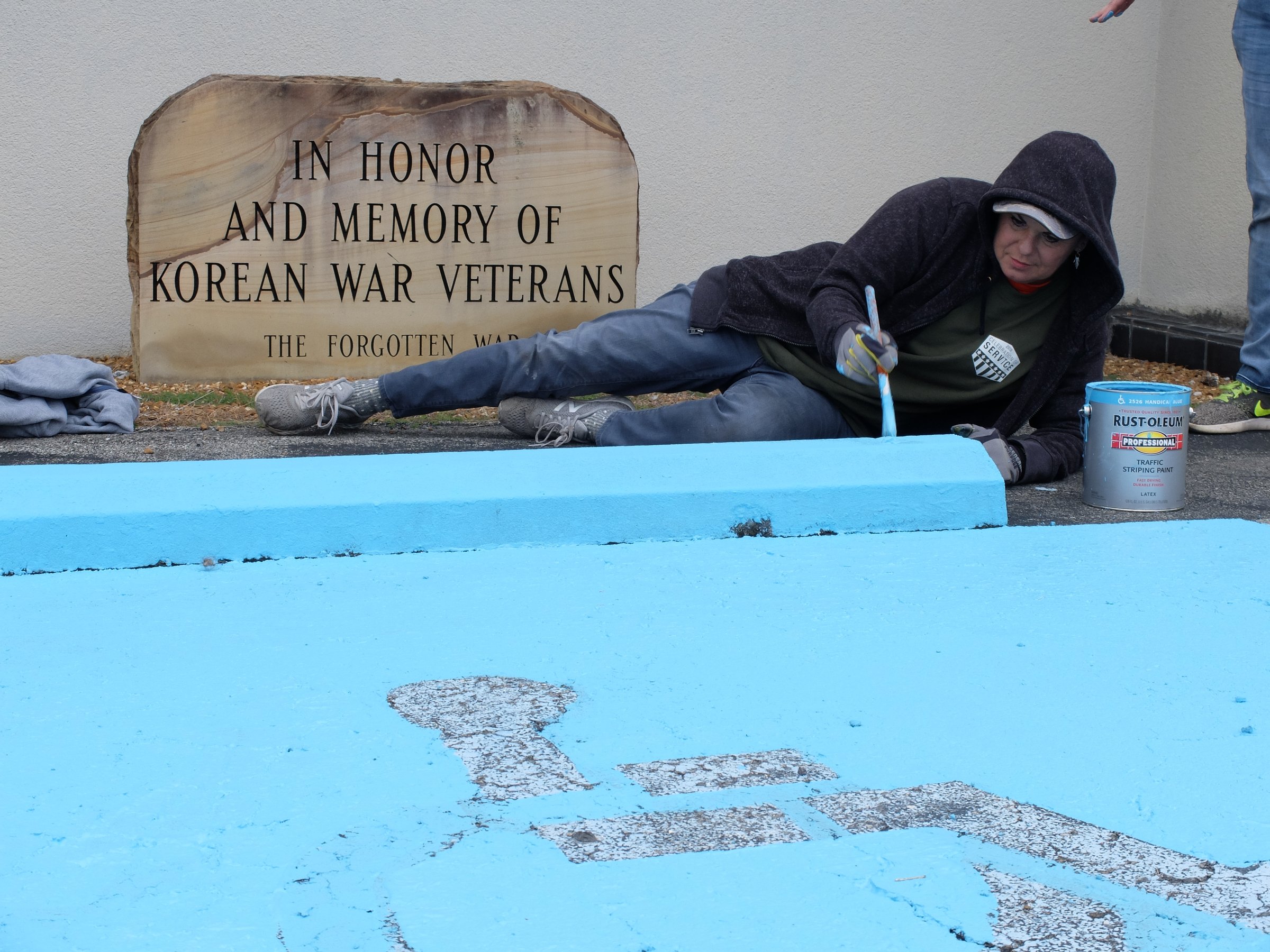 Trayce West paints a handicap parking spot during Home Depot's annual day of service for veterans. More than 100 members of Team Depot, the retailer's associate-lead volunteer force, completed the work on their day off.
