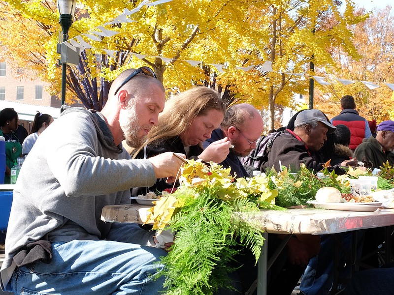 Barry Dent, left, Natasha Newman and Tony Newman enjoy lunch in the middle of Martin Luther King Boulevard Monday as hundreds gather for the fifth annual Gratefull Chattanooga community-wide potluck. The event, founded by local nonprofit Causeway, seeks to unite Chattanoogans from all walks of life to share a meal.