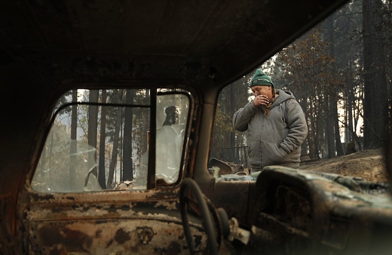 In this Nov. 15, 2018, photo, Troy Miller wipes his eyes as he walks beside a burned out car on his property in Concow, Calif. Miller said he tried to evacuate when the Camp Fire came roaring through the area, but had to turn back when the roads were blocked with debris and fire. A small group of residents who survived the deadly wildfire are defying evacuation orders and living in the burn zone. (AP Photo/John Locher)

