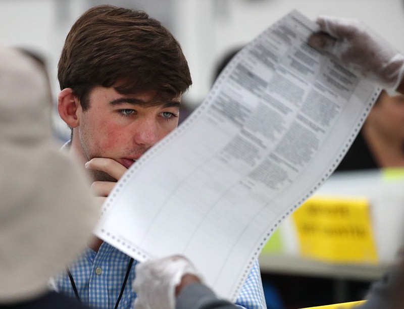 FILE- In this Friday, Nov. 16, 2018, file photo a Republican observer looks at a ballot during a hand recount at the Broward County Supervisor of Elections office in Lauderhill, Fla. Florida Republican Gov. Rick Scott is leading incumbent Sen. Bill Nelson in the state's contentious Senate race. Official results posted by the state on Sunday, Nov. 18, showed Scott ahead of Nelson following legally-required hand and machine recounts. State officials will certify the final totals on Tuesday. (AP Photo/Wilfredo Lee, File)

