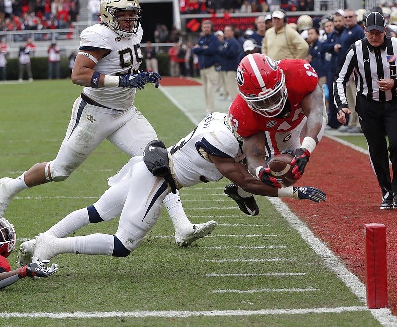Georgia running back Elijah Holyfield dives for an 8-yard touchdown run as Georgia Tech defensive back Jaytlin Askew tries to make the tackle during the second quarter of Saturday's game in Athens. Holyfield finished with 79 yards on nine carries, and D'Andre Swift led the Bulldogs with 105 on 14.