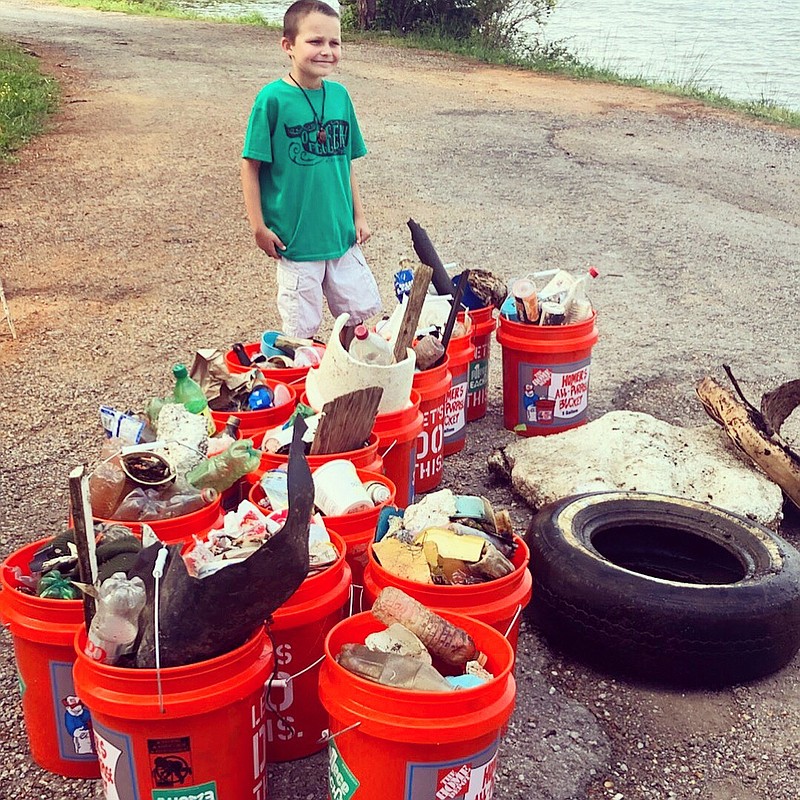 Cash Daniels, 9, poses with buckets used to collect trash during the river cleanups he leads each month. (Contributed photo)