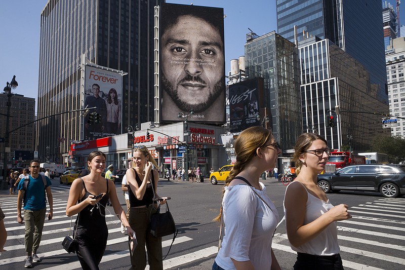 People in New York City walk past a Nike advertisement featuring former San Francisco 49ers quarterback Colin Kaepernick, known for kneeling during the national anthem to protest police brutality and racial inequality.