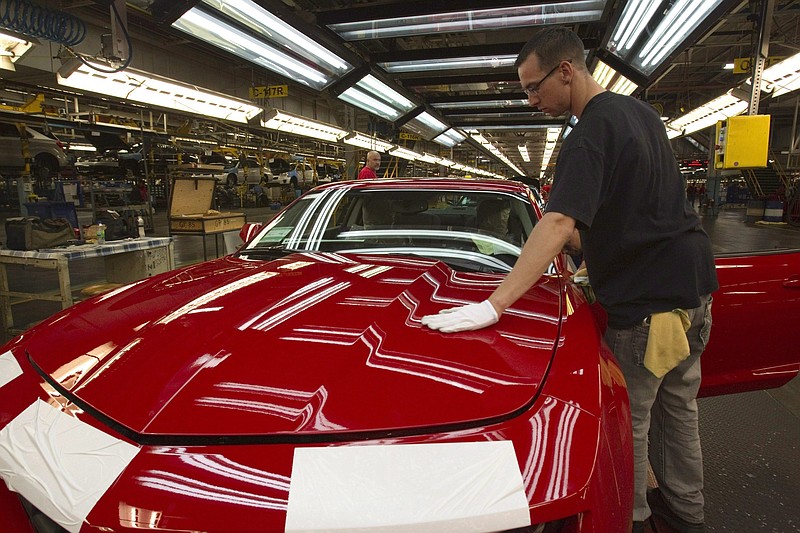 FILE - In this June 10, 2011, file photo, a worker checks the paint on a Camaro at the GM factory in Oshawa, Ontario. General Motors is closing a Canadian plant at the cost of about 2,500 jobs, but that is apparently just a piece of a much broader, company-wide restructuring that will be announced as early as Monday, Nov. 26, 2018. (Frank Gunn/The Canadian Press via AP, File)