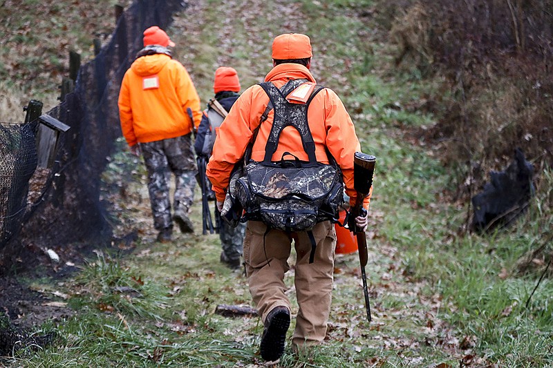 Santo Cerminaro, right, follows his son, Dominick Cerminaro, left, and grandson, Santo Cerminaro, 11, into the woods to go deer hunting on the first day of rifle season in Zelienople, Pa., on Monday.