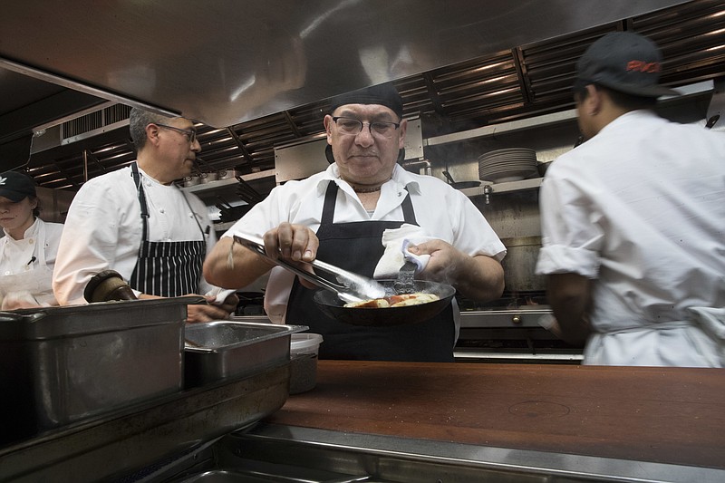 In this Tuesday, Nov. 27, 2018 photo, Chef Jacinto Guadarrama, left, prepares dishes with the help of the kitchen staff at Gotham Bar and Grill in New York. Some small businesses are making hard choices as labor and other costs keep rising. Gotham’s hourly wages have gone up along with the city’s minimum wage, which rose $2 an hour to $13 last December and will reach $15 this Dec. 31. The restaurant is also paying more for ingredients, especially eggs and other dairy items, key dessert components. (AP Photo/Mary Altaffer)