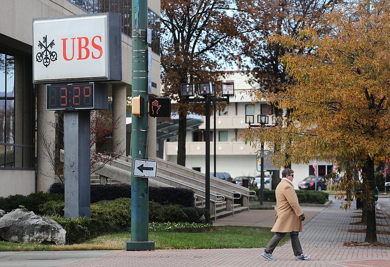 A pedestrian walks past the UBS Financial Services sign as it reads 32 degrees Wednesday, November 28, 2018 in Chattanooga, Tennessee. While the weather was in the 30s throughout the day, temperatures are expected to get warmer heading into the weekend.