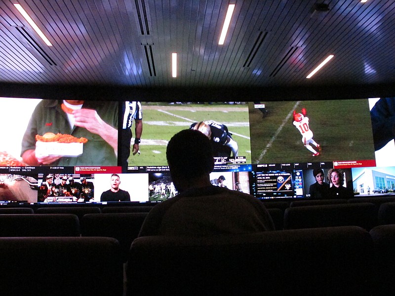 In this Nov. 20, 2018, photo a customer watches video screens at the sports betting facility at Resorts Casino in Atlantic City, N.J. Professional sports leagues that once vehemently fought sports betting are now partnering with gambling companies to get in on it now that it's legal. (AP Photo/Wayne Parry)