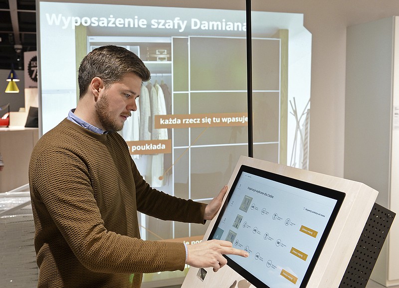 In this Thursday Nov. 22, 2018 photo, Andreas Flygare, the project manager for the new Warsaw Ikea store presents a system projecting furniture interior a wall, in Warsaw, Poland. The new Ikea store, recently opened in a city shopping mall, is part of a global strategy by the Swedish furniture chain to adapt to a changing consumer environment by opening small, accessible stores in city centers to complement the traditional large out-of-town store stores. (AP Photo/Alik Keplicz)