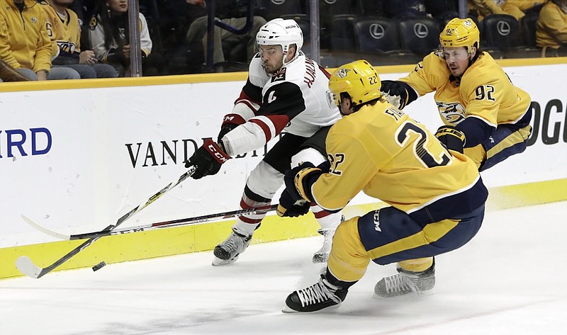 Arizona Coyotes defenseman Niklas Hjalmarsson, in white, chases after the puck with Nashville Predators left wing Kevin Fiala, front, and center Ryan Johansen in the second period of Thursday night's game in Nashville.
