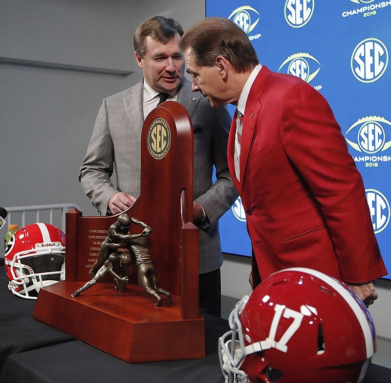 Georgia coach Kirby Smart, left, and Alabama coach Nick Saban talk Friday near the SEC football championship trophy during festivities in Atlanta ahead of Saturday's league title game at Mercedes-Benz Stadium.