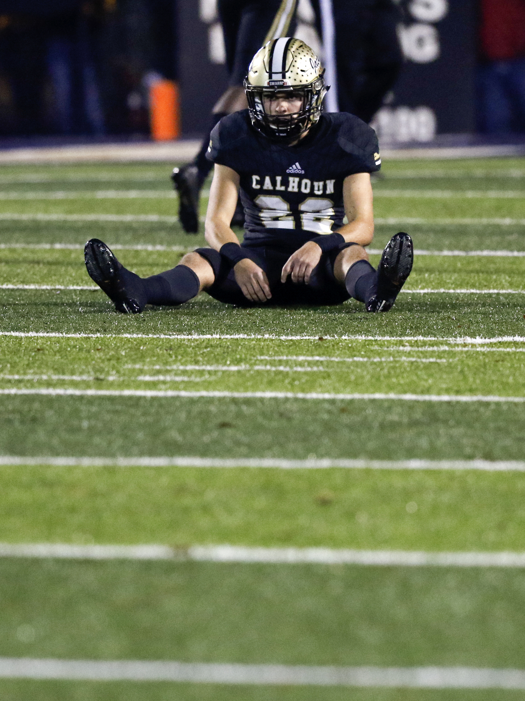 Calhoun's Aaron Hayes sits on the turf at Phil Reeve Stadium after having a punt blocked by Peach County during a GHSA Class AAA semifinal on Friday night in Calhoun, Ga. Peach County won 22-7.