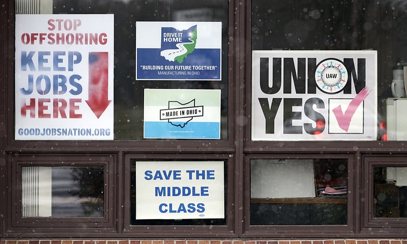 In this Nov. 27, 2018 photo, signs hang from windows at the UAW Local 1112 union hall, in Lordstown, Ohio. It was working-class voters who bucked the area's history as a Democratic stronghold and backed Donald Trump in 2016, helping him win the White House with promises to put American workers first and bring back disappearing manufacturing and steel jobs. Whether they stick with him after this week's GM news and other signs that the economy could be cooling will determine Trump's political future. (AP Photo/Tony Dejak)

