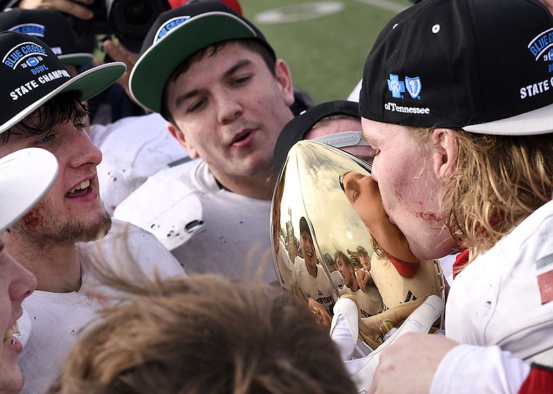 Whitwell High School football senior standout Hudson Petty, left, holds the TSSAA Class 1A BlueCross Bowl championship trophy as Josh Wingo kisses it with Thundur Roberts in the background Saturday afternoon at Tennessee Tech in Cookeville. Whitwell beat Cornersville 7-6 to complete an undefeated season and win the program's first state title in its first appearance in a championship game, and Petty was named the game's MVP.