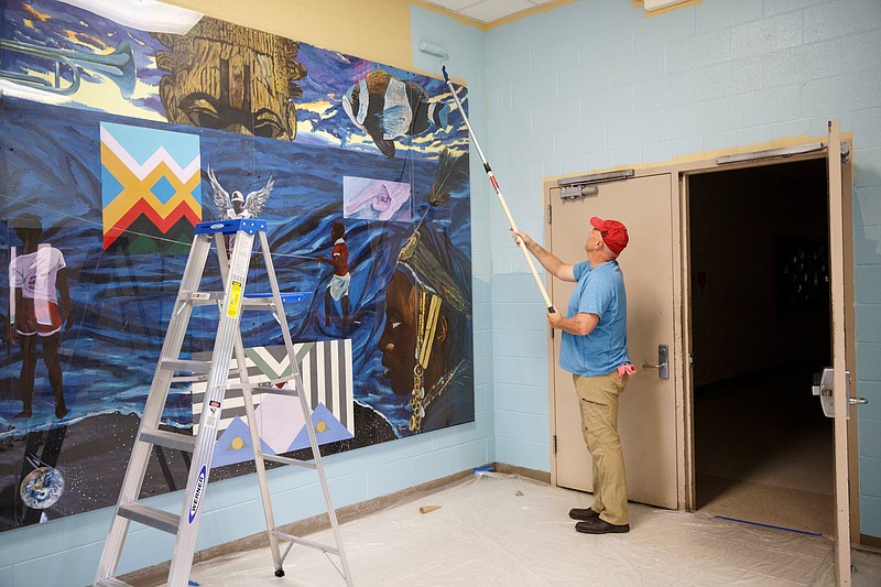 Kevin Shumaker paints a hallway.