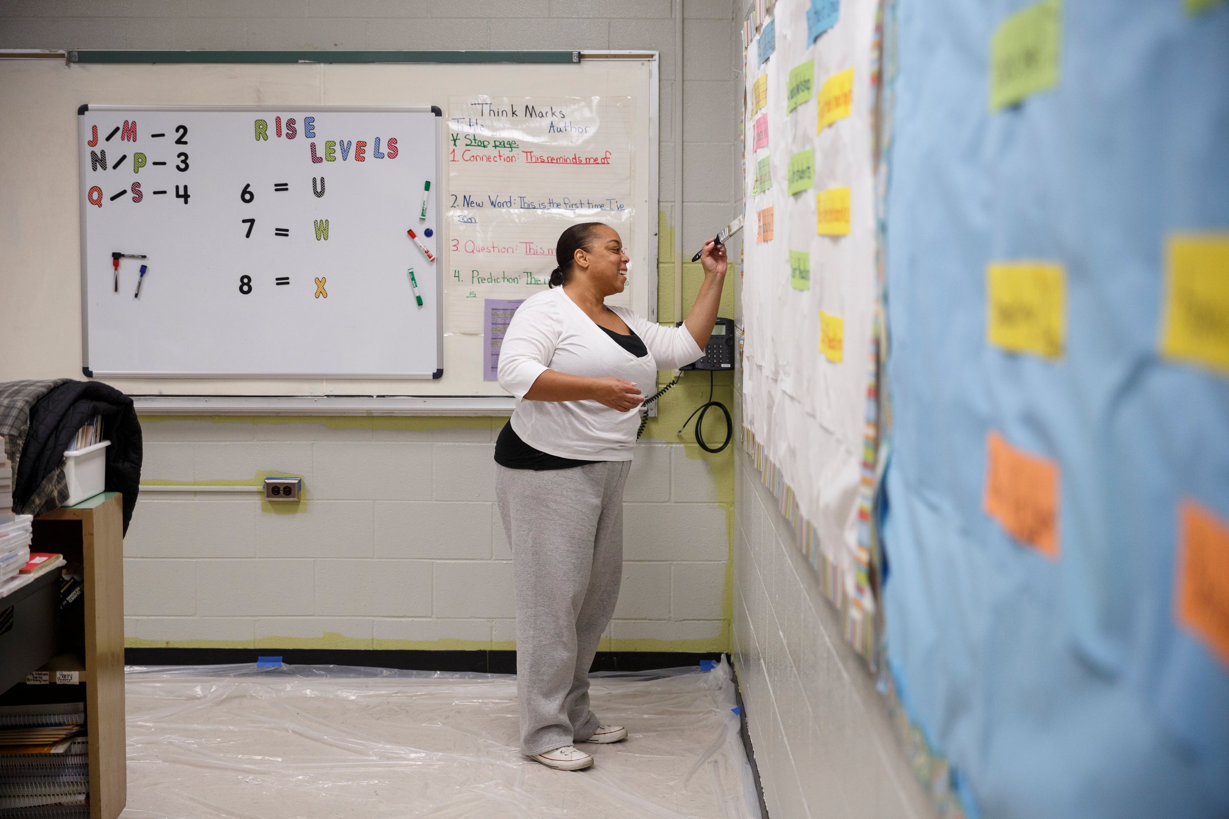 Tanea Marshall paints a classroom wall.