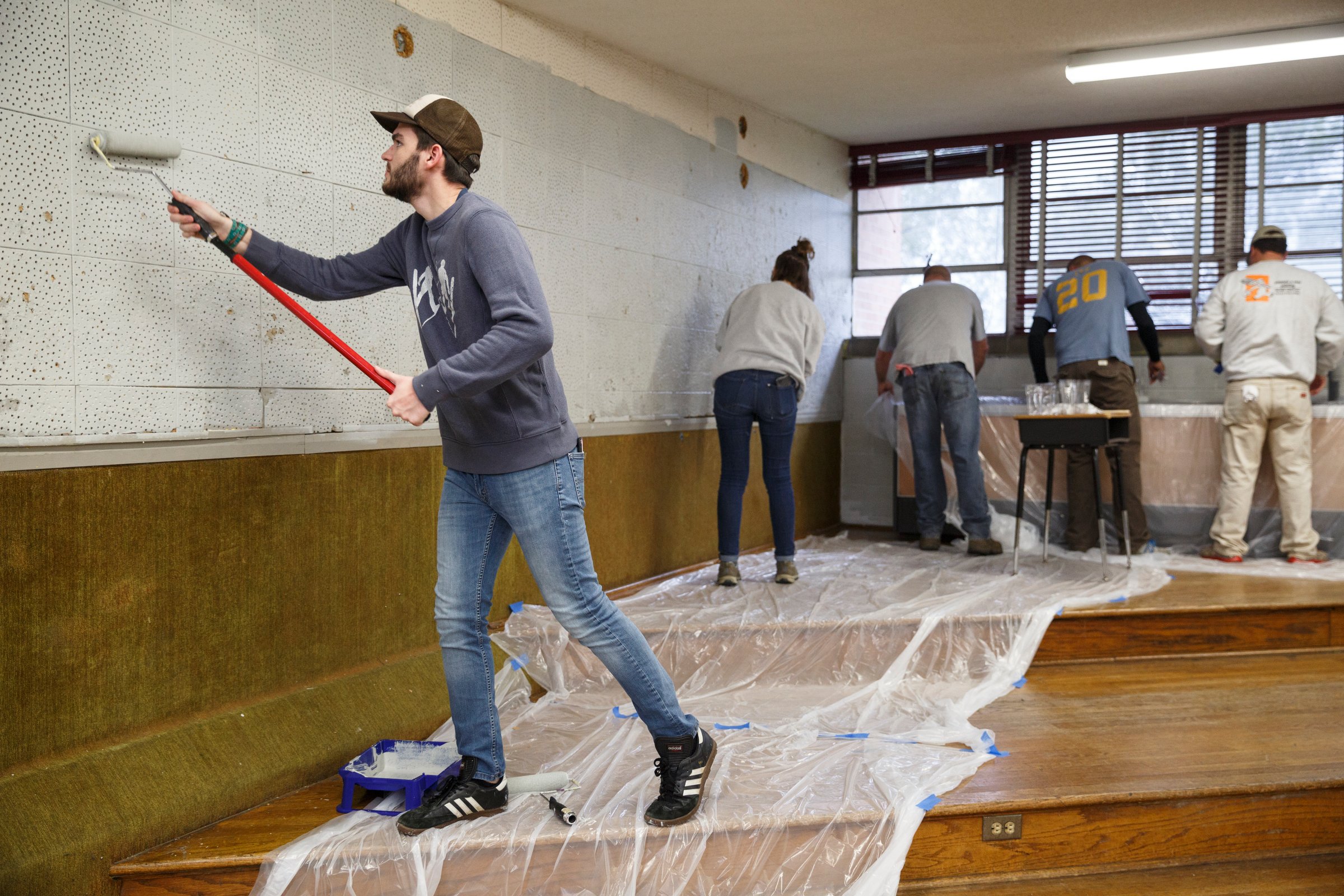 John Davis paints the band room wall.