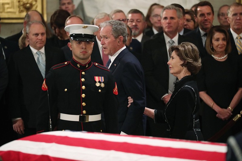 Former President George W. Bush, with his wife former first lady Laura, walks past the casket of his father, former President George H.W. Bush at the Capitol in Washington, Monday, Dec. 3, 2018. (Jonathan Ernst/Pool Photo via AP)

