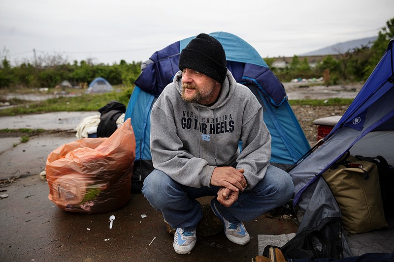 Malcolm Amicarelli kneels outside the tent he shares with Agnie Wise in a homeless encampment behind the city's wellness center on East 11th Street on Friday, April 6, 2018, in Chattanooga, Tenn. City service coordinators were on site at the camp Friday to help residents find temporary housing, because the camp is located on a toxic brownfield. 