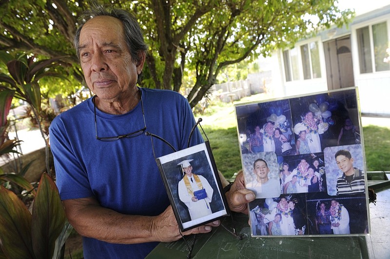 FILE - In this July 10, 2017, file photo, Clifford Kang, father of soldier Ikaika E. Kang, poses with photos of his son in Kailua, Hawaii. Ikaika E. Kang, an active-duty U.S. soldier, arrested on terrorism charges that accuse him of pledging allegiance to the Islamic State group, is scheduled to be sentenced, Tuesday, Dec. 4, 2018. (Bruce Asato/Honolulu Star-Advertiser via AP, File)

