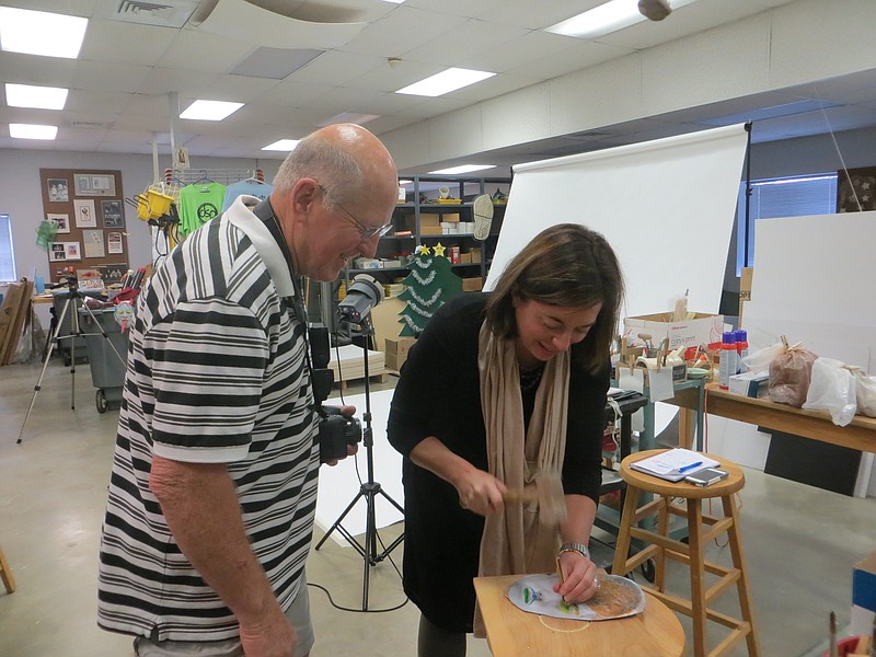 Dennis Wilkes, left, art director at Orange Grove Center, puts Angie Supan to work on an art project on a River Gallery tour of the Orange Grove Center art department. Supan is assistant director of sales at the gallery. / Contributed photo from River Gallery