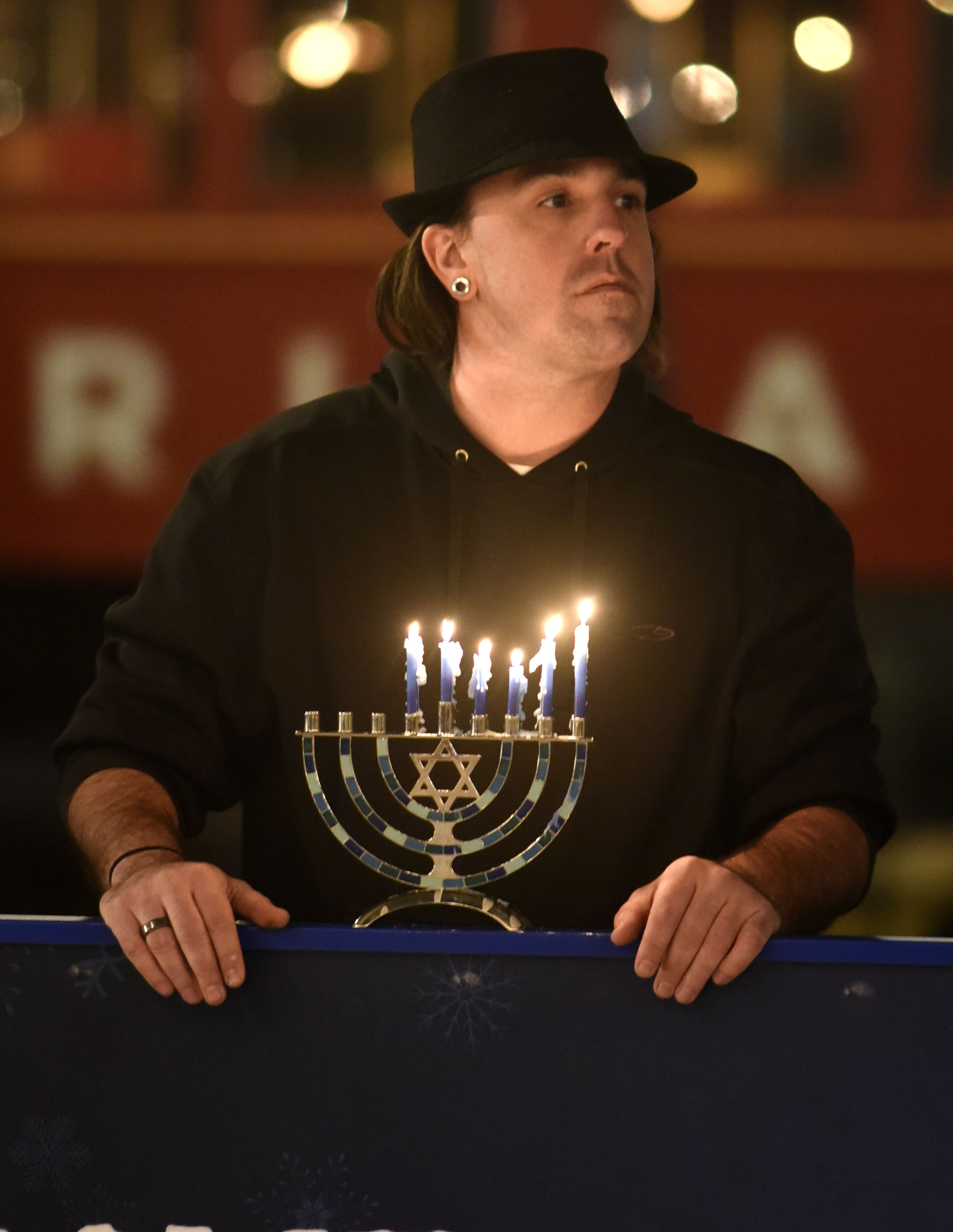 A man watching from the side of the ice rink with his own Menorah. Chabad of Chattanooga celebrated Hanukkah with A Menorah topped car parade to the Choo Choo and the lighting of the Menorah at Ice on the Landing on December 6, 2018.