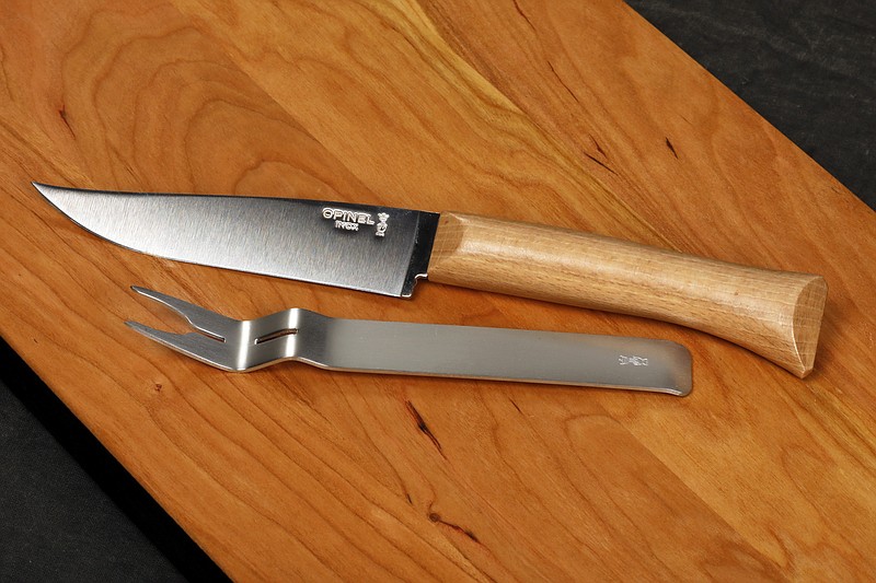 This Nov. 13, 2018 photo shows an Opinel Cheese Knife and Fork Set on a JK Adams Cherry Cheese Server in New York. It is a compact set of an interlocking fork and cheese knife made from stainless steel and a blond beech-wood handle. (AP Photo/Richard Drew)