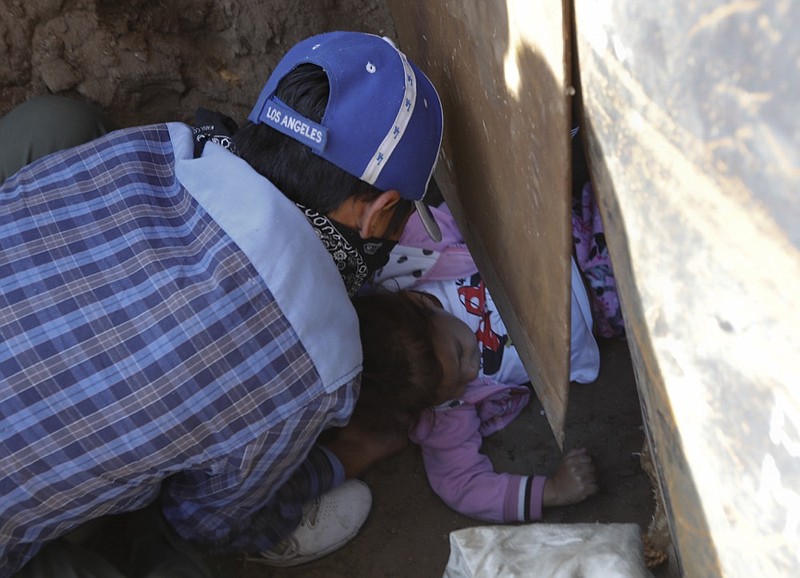 Honduran migrant Charlot Andrea, 3, is passed under the U.S. border wall to her 19-year-old mother Rachel Rivera, who had already crossed, in order to surrender to the U.S. border patrol and request asylum, from Playas de Tijuana, Mexico, Tuesday, Dec. 4, 2018. Weeping as she stayed behind in Tijuana with her Mexican husband, the little girl's grandmother Yesenia said her daughter and granddaughter joined the migrant caravan to flee an abusive husband back in Honduras. (AP Photo/Rebecca Blackwell)

