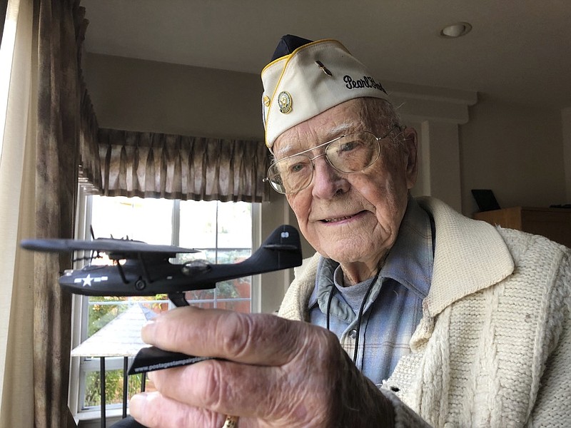 Retired U.S. Navy Cmdr. Don Long holds up a replica of the military seaplane he was standing watch on when Japanese warplanes attacked Hawaii 77 years ago, Friday, Dec. 7, 2018 at his home in Napa, California. Long was alone on the anchored plane in the middle of Kaneohe Bay, across the island from Pearl Harbor, when the attack happened, watching from afar as the bombs and bullets killed and wounded thousands. When the gunfire finally reached his plane, setting the aircraft ablaze, he jumped into the water and found himself swimming through fire to safety. (AP Photo/Eric Risberg)

