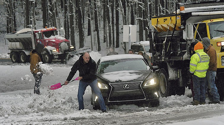 An unidentified driver shovels a path for the driver of a car stuck and blocking the ramp from I-40 westbound to Cary Towne Blvd. in Cary, N.C. Sunday morning, Dec. 9, 2018.