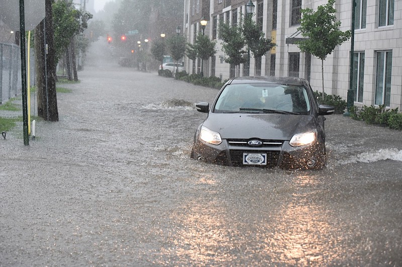 Staff photo by Tim Barber Stormwater blows the lid off in the 900 block of Douglas Street in June, filling the roadway with more than a foot of water.