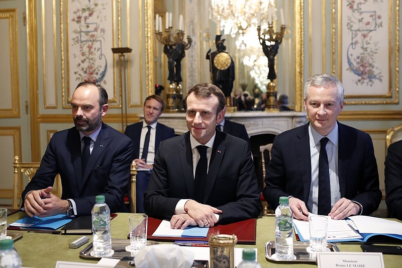 France's President Emmanuel Macron, center, France's Prime Minister Edouard Philippe, left, and France's Finance Minister Bruno Le Maire, right, attend a meeting with the representatives of the banking sector at the Elysee Palace, in Paris, Tuesday, Dec.11, 2018. Macron met with representatives of the banking sector to discuss responses to bring to the Yellow Vest protesters' claims. The meeting comes one day after he speed up tax relief and to boost the purchasing power of struggling workers and retirees in a national television address. (AP Photo/Thibault Camus, Pool)