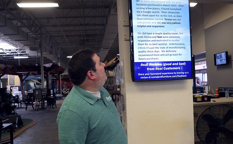 In this Tuesday, Dec. 11, 2018, photo Brad Schweig, co-owner of Sunnyland Furniture, looks at a video screen displaying a review of his business in Dallas. (AP Photo/LM Otero)