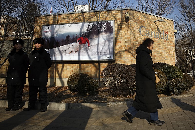 A woman walks by policemen stand guard outside the Canadian Embassy in Beijing, Friday, Dec. 14, 2018. Canada is being battered by diplomatic ill winds. First, President Donald Trump attacked Canada on trade. Then Saudi Arabia punished it for speaking up for human rights. Now China has the country in its cross-hairs, detaining two Canadians in apparent retaliation for the arrest of a top Chinese tech executive on behalf of the U.S. Canada's normally reliable ally to the south has left it high and dry. (AP Photo/Andy Wong)